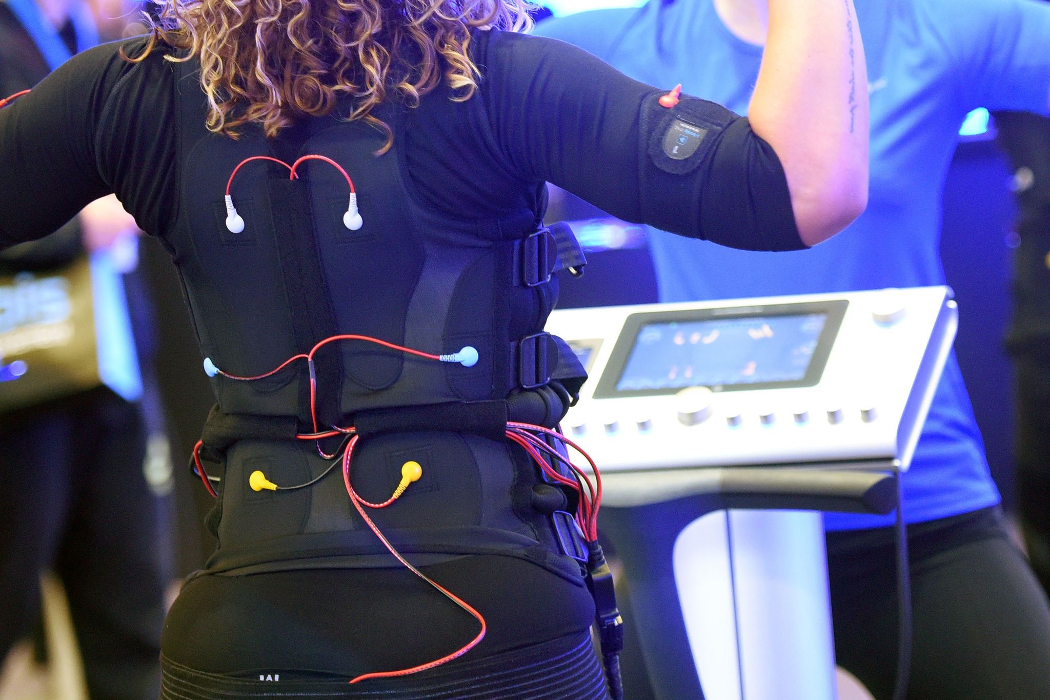 Bei einem EMS-Training trägt man eine verkabelte Weste und Manschetten, über die elektrische Impulse an den Körper weitergeleitet werden.