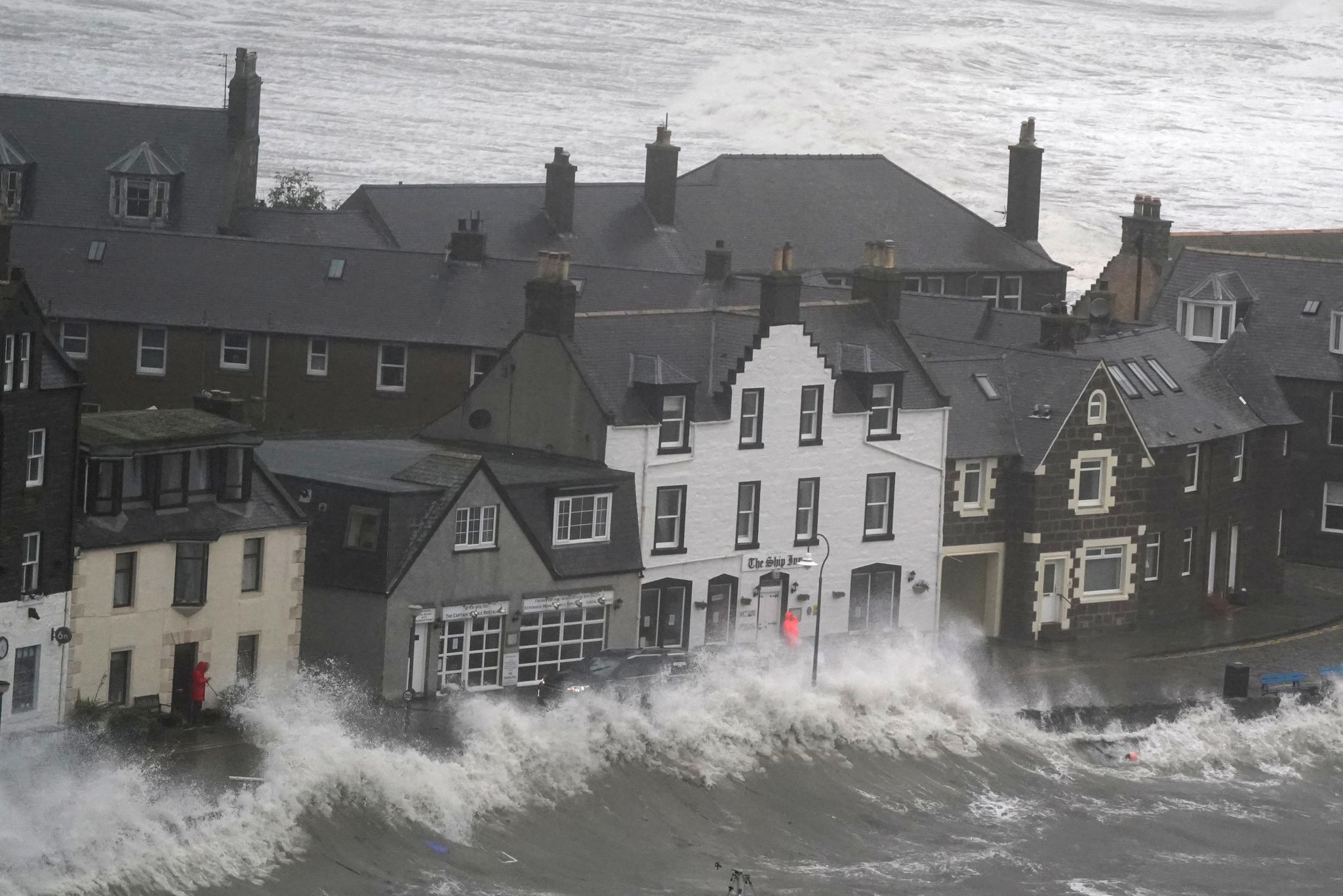 Hohe Wellen brechen an einer Kaimauer an der schottischen Nordseeküste.