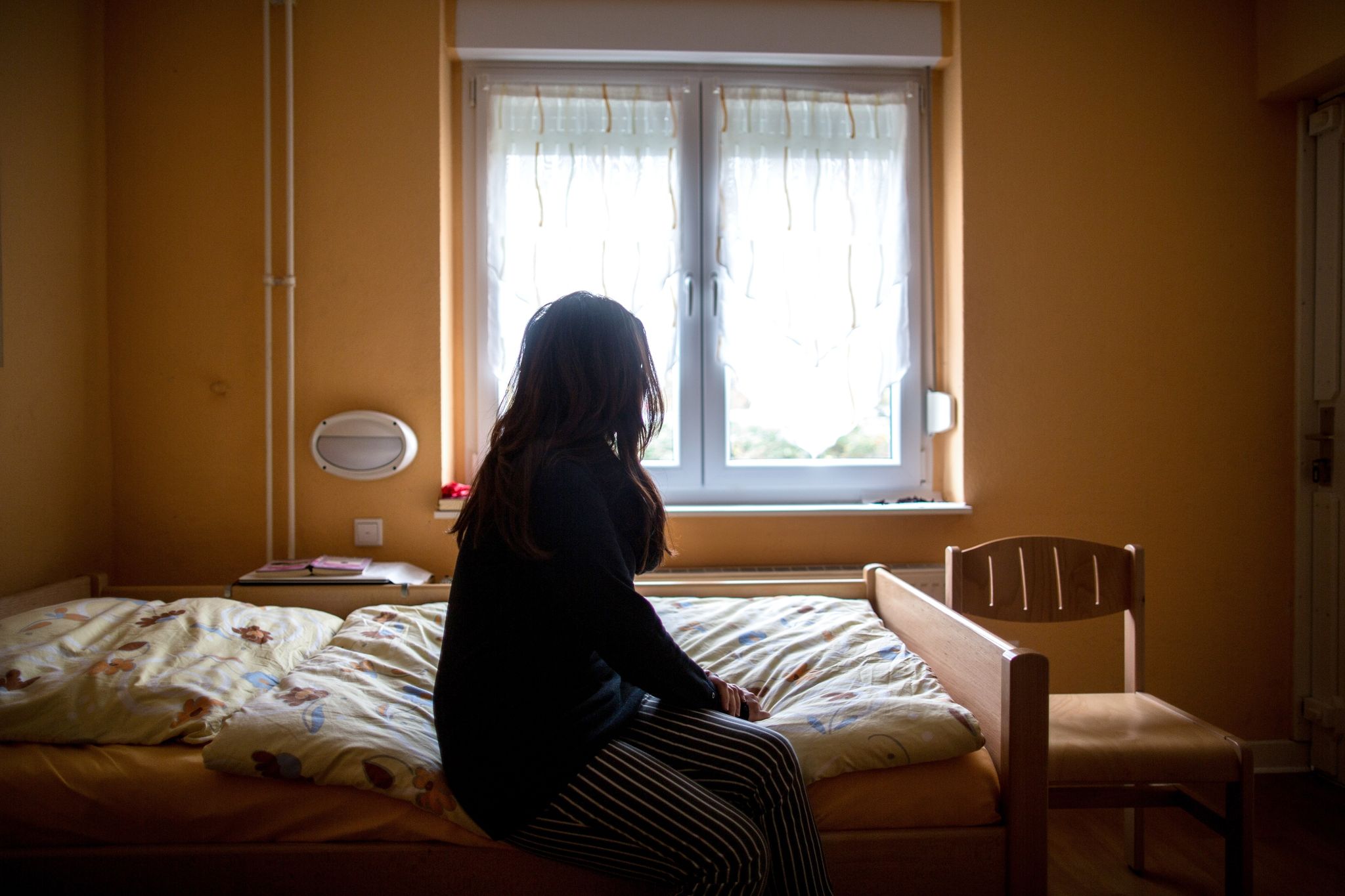 Eine Frau sitzt in einem Frauenhaus auf einem Bett. Tausende Frauen und Kinder haben auch 2022 zeitweilig Schutz in Schutzeinrichtungen gesucht.