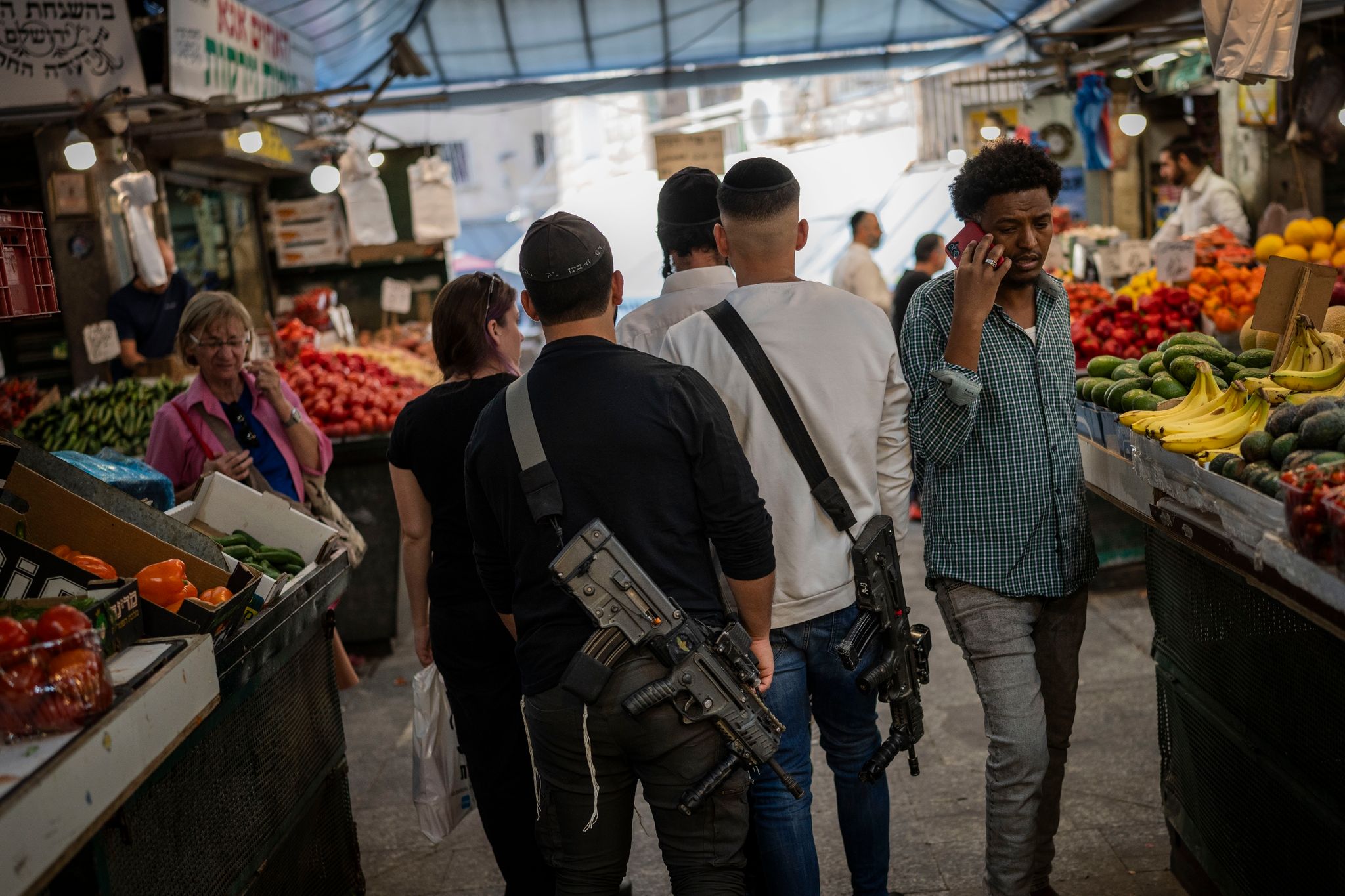 Israelische Soldaten, die gerade nicht im Dienst sind, gehen mit ihren Gewehren über den Mahane Yehuda Markt in Jerusalem.