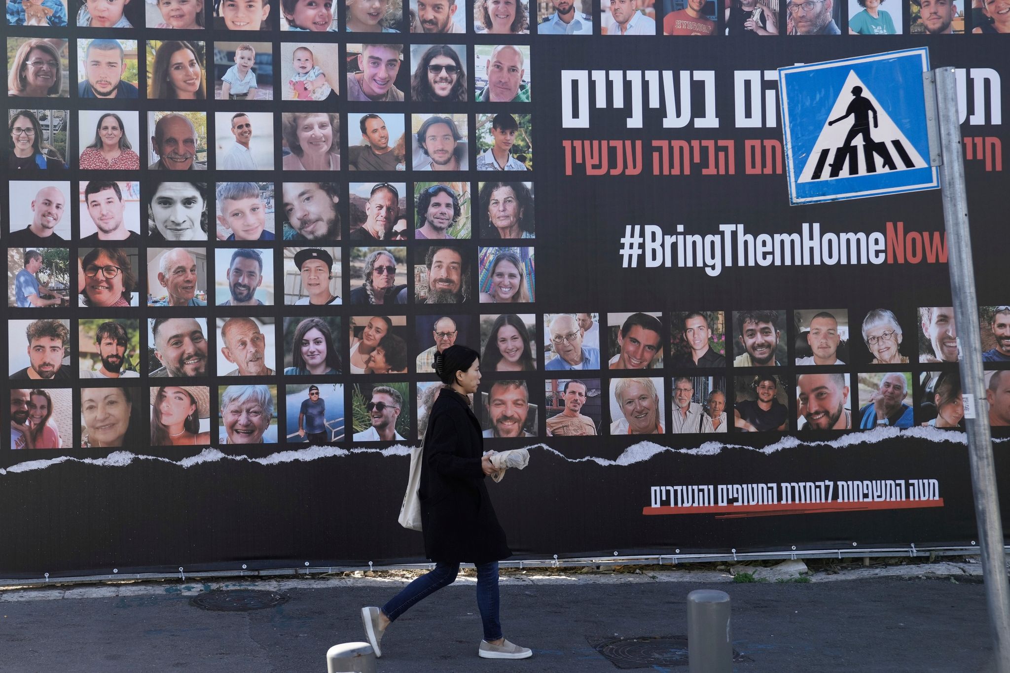 Eine Frau geht in Jerusalem an einem Plakat vorbei, das die Rückkehr der etwa 240 Geiseln fordert.