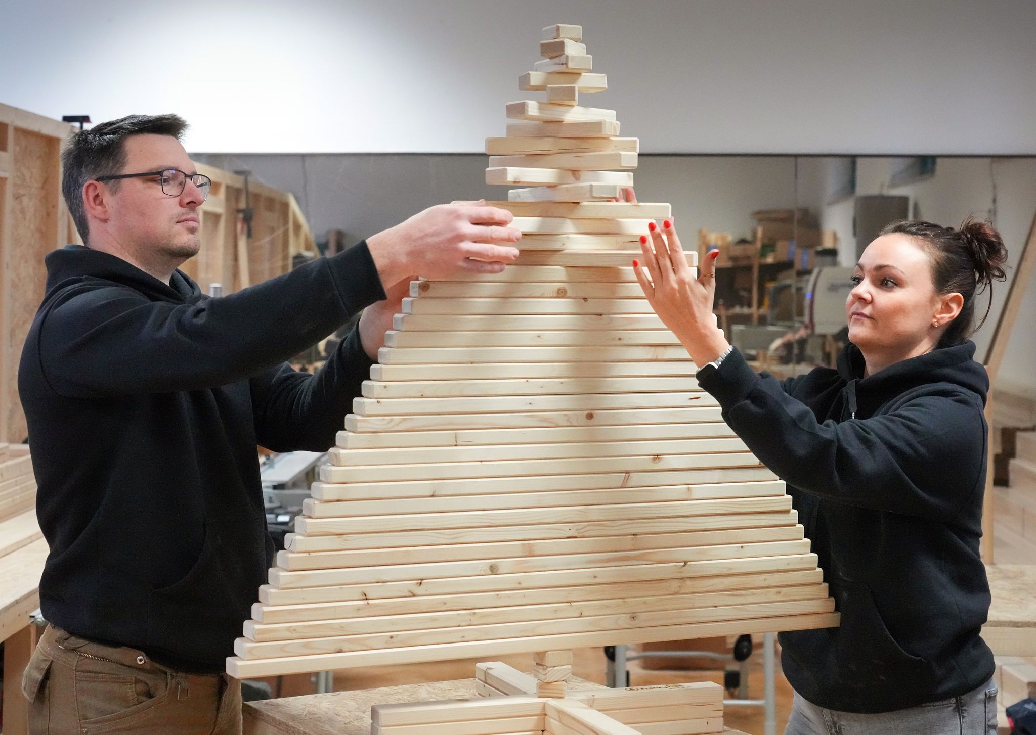 Der Bautechniker Thilo Tolkmitt und Betriebswirtin Ulrike Thunack setzen einen Baum aus Holzlatten zusammen.