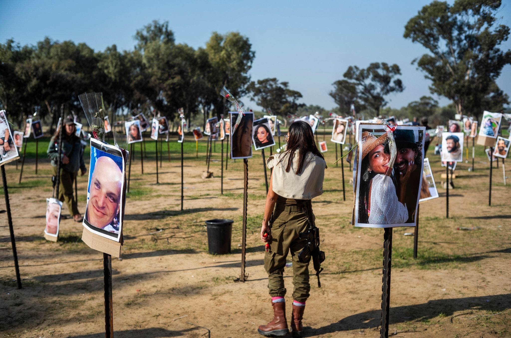 Israelische Soldatinnen stehen zwischen Fotos getöteter Israelis am Ort des Hamas-Massakers beim Musikfestival in der Negev-Wüste am 7. Oktober.