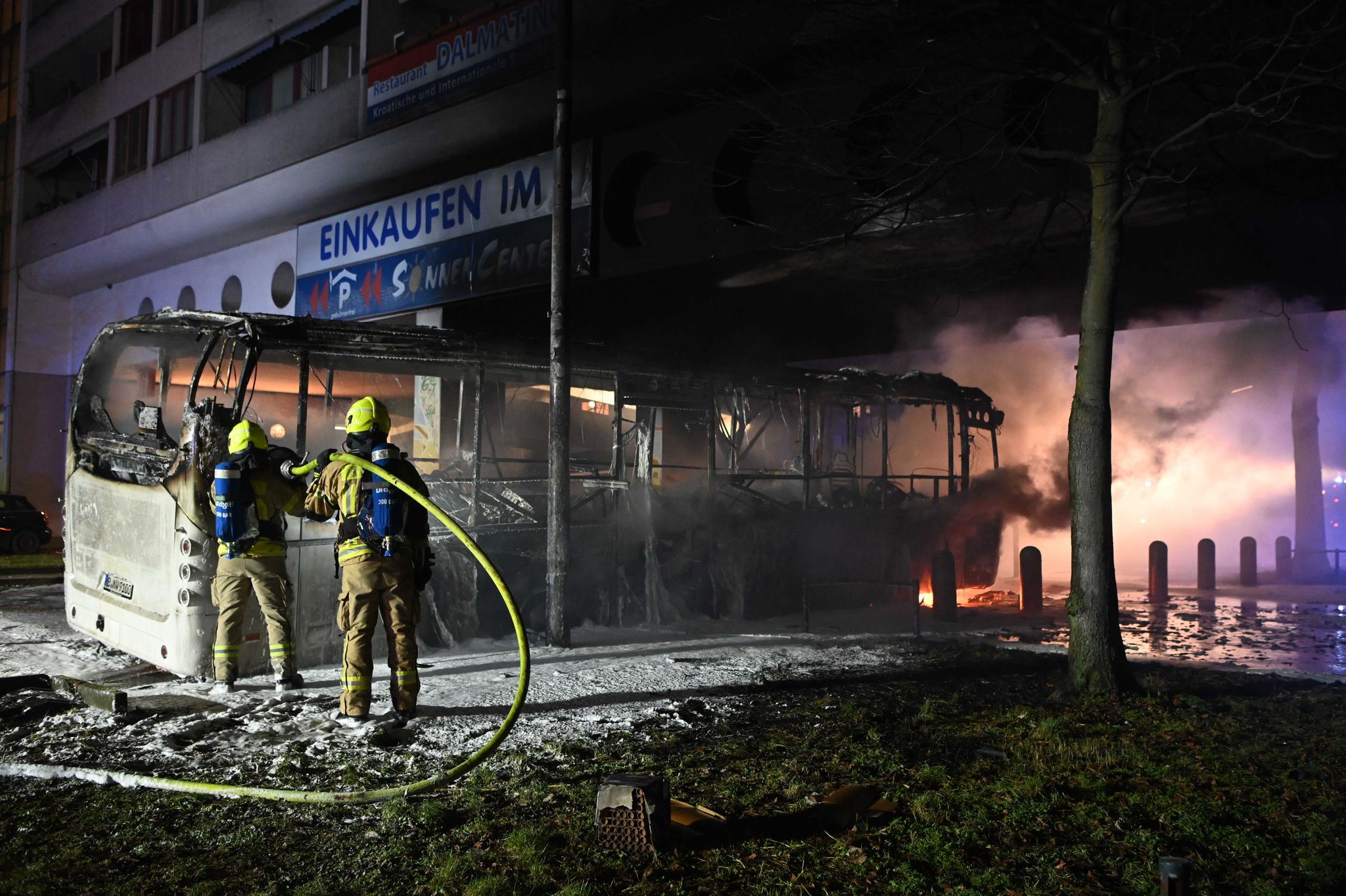 Einsatzkräfte der Feuerwehr löschen in der Silvesternacht 2022/2023 im Bezirk Berlin-Neukölln einen brennenden Bus, der von Unbekannten angezündet worden war.