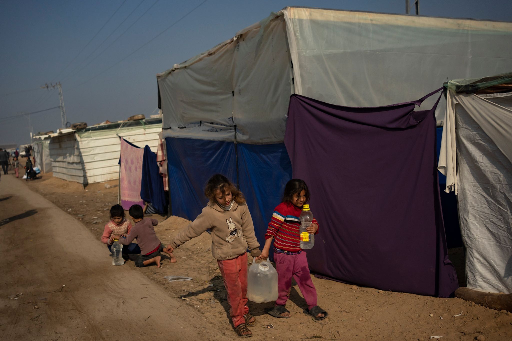 Palästinensische Kinder tragen Wasser in einem behelfsmäßigen Zeltlager.