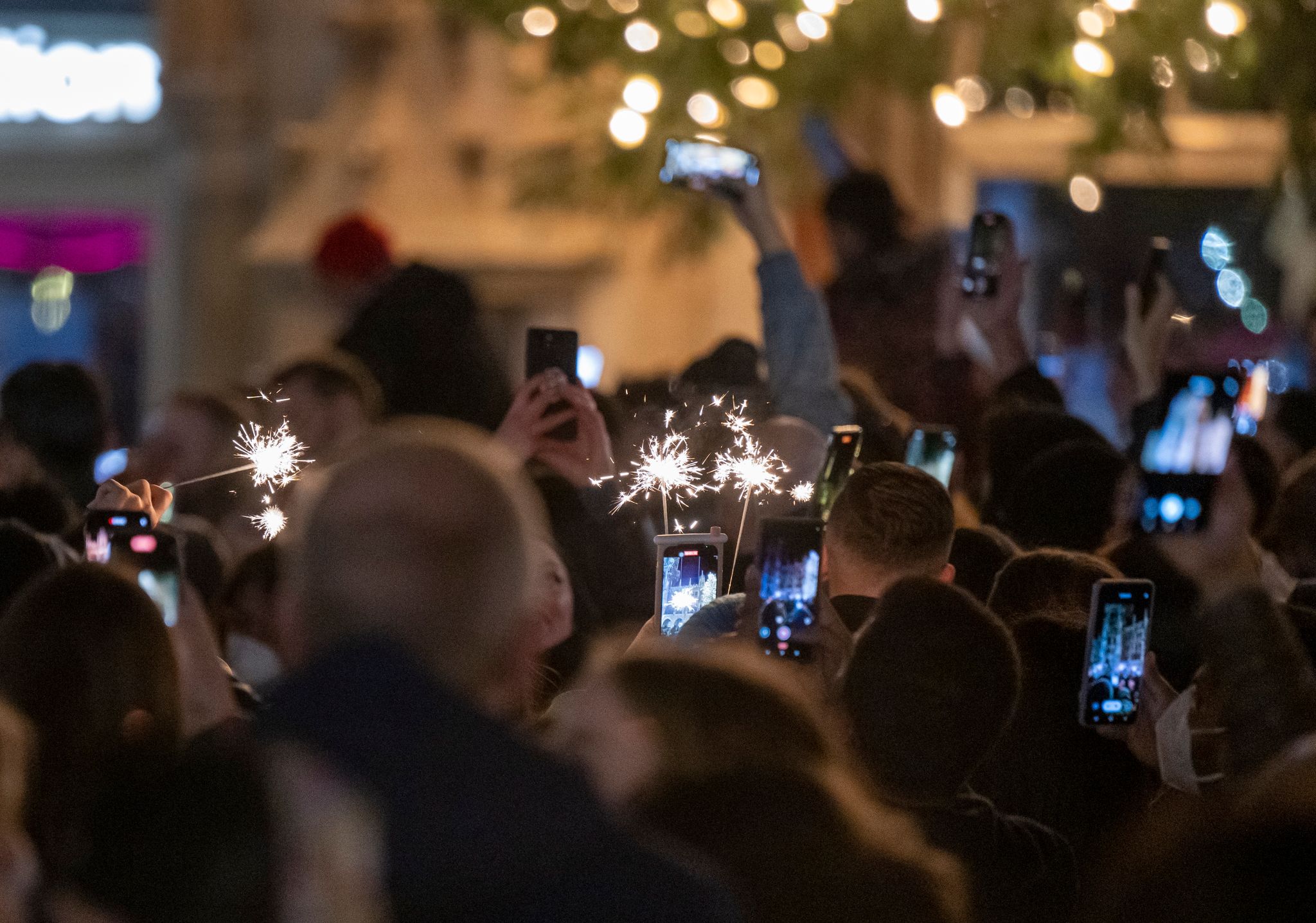 Menschen machen Fotos mit ihren Smartphones, während sie den Jahreswechsel feiern.