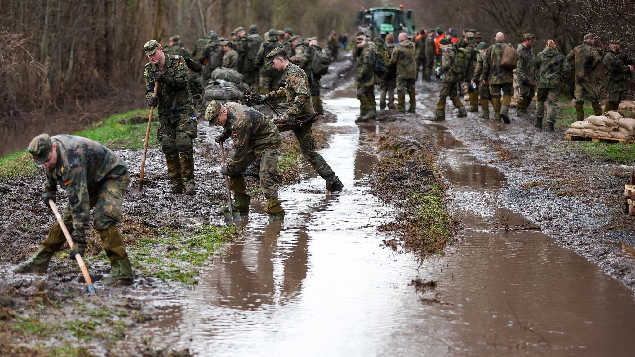 Soldatinnen und Soldaten der Bundeswehr sichern einen Deich an der Helme mit Sandsäcken.