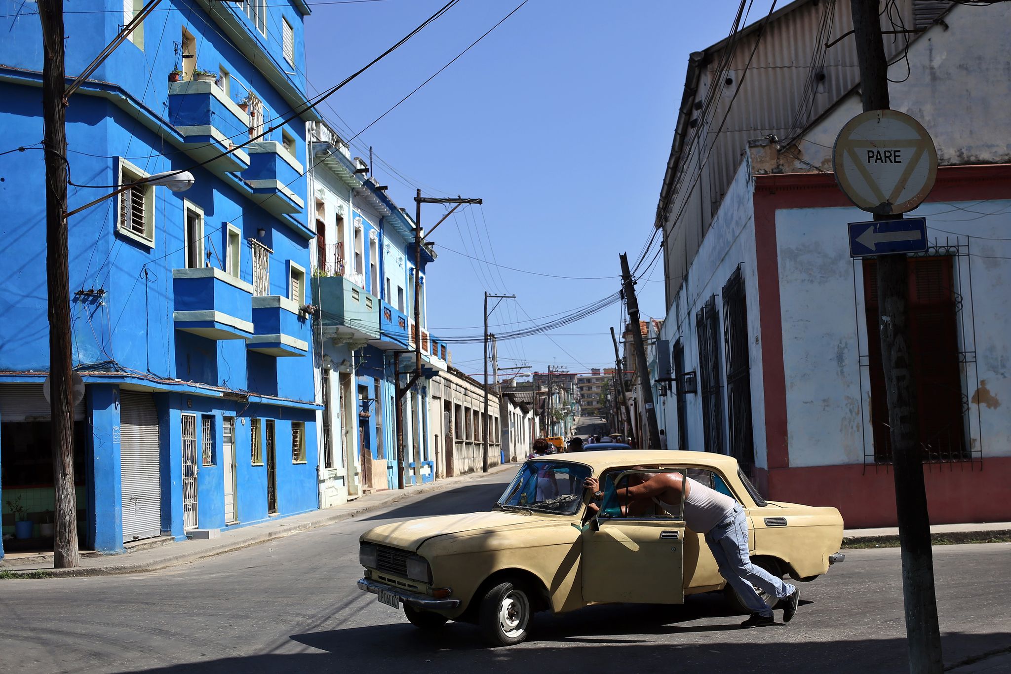 Ein Mann schiebt sein kaputtes Auto durch eine Straße in der kubanischen Hauptstadt.
