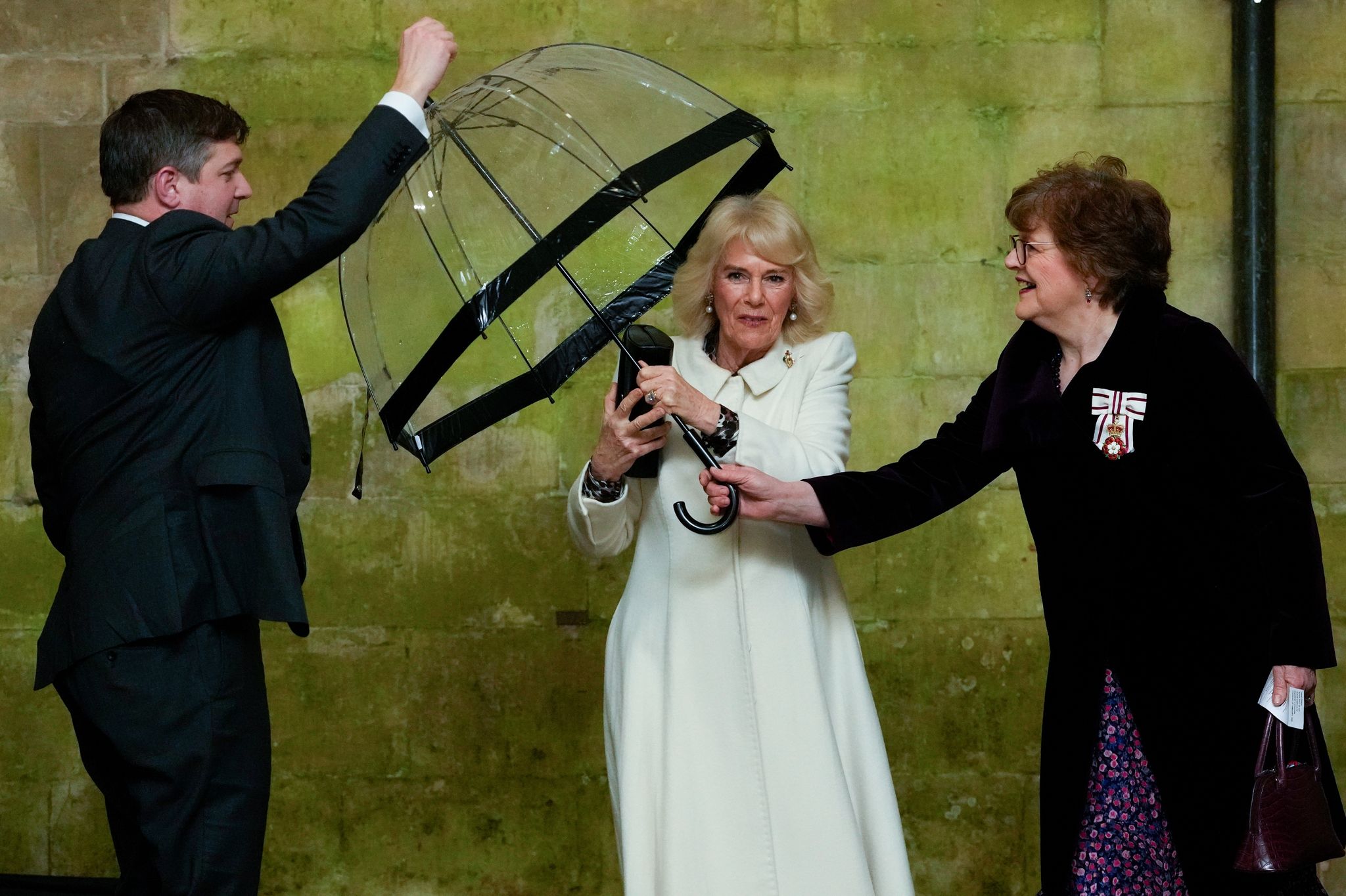 Königin Camilla reicht einem Adjutanten ihren Regenschirm, als sie zu einem musikalischen Abend in der Kathedrale von Salisbury eintrifft, um die Arbeit lokaler Wohltätigkeitsorganisationen zu feiern.