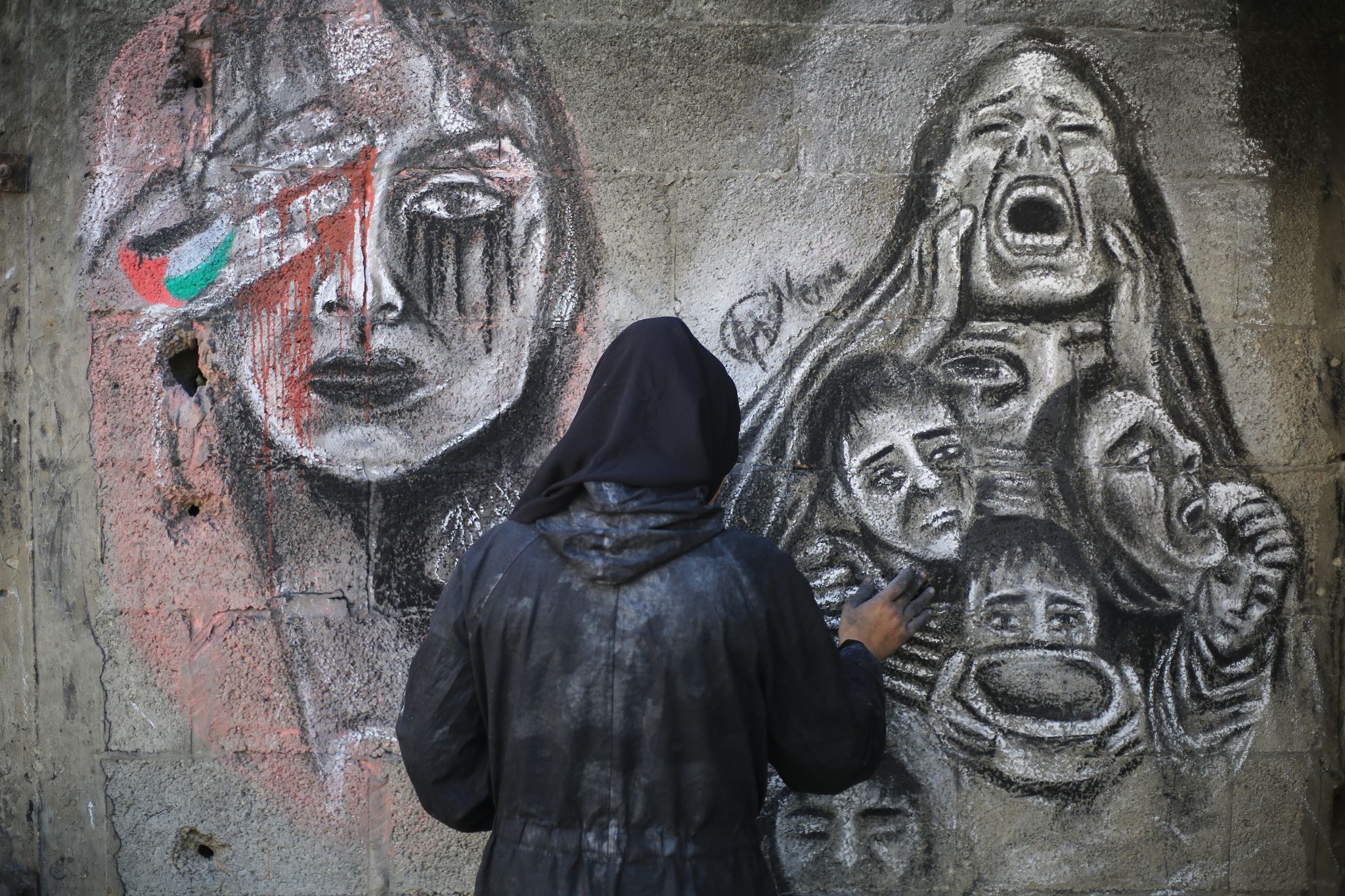 Die 21-jährige palästinensische Künstlerin Menna Hamouda bemalt mit Kohle die Wände einer Schule im Gazastreifen, in die sie umgesiedelt wurde und macht damit auf das Leid der Zivilbevölkerung in dem abgeriegelten Küstengebiet aufmerksam.