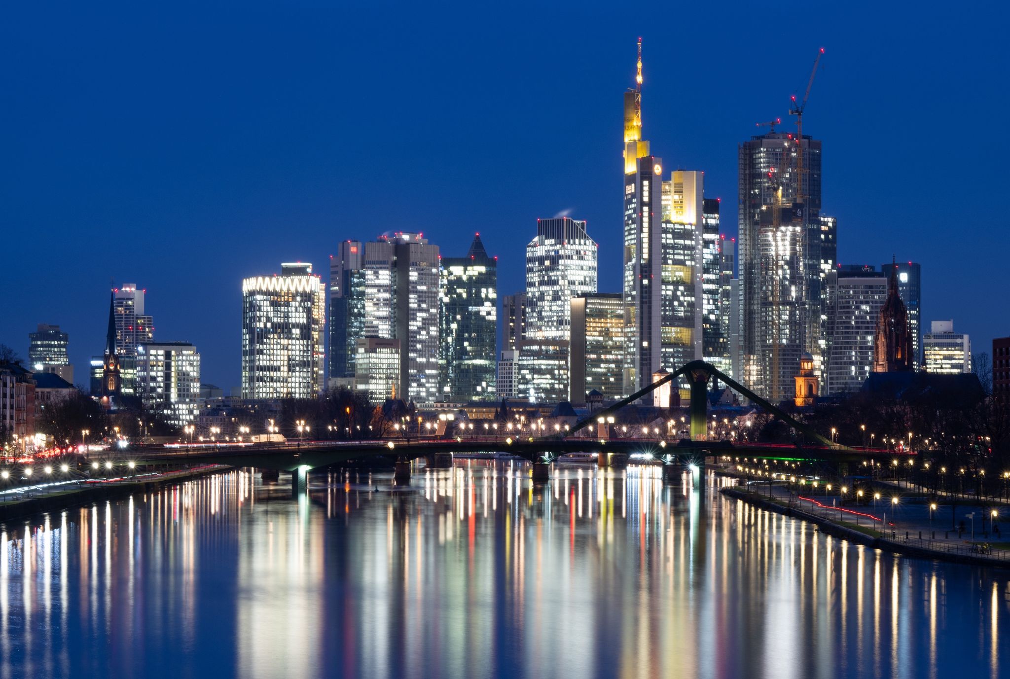 Die Lichter der Bankenskyline von Frankfurt am Main leuchten im letzten Licht des Tages.